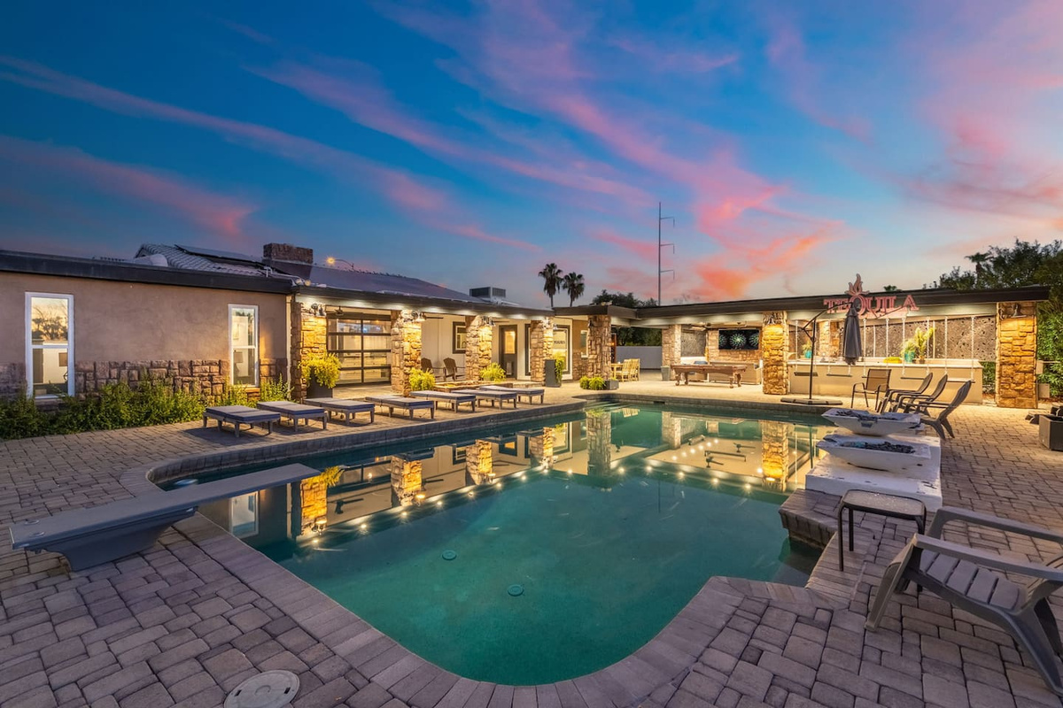 The full pool glimmers at dusk beneath a pink sky, with the "Tequila" sign lit in the distance.