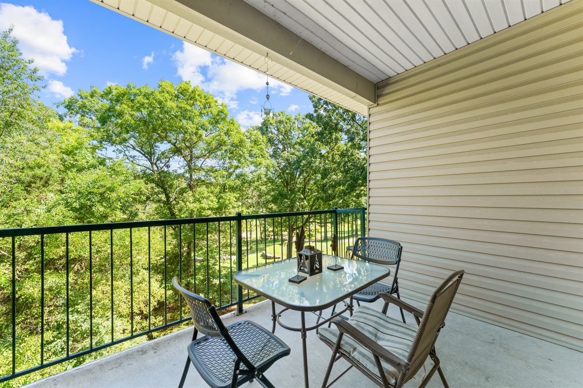 Covered private deck with outdoor seating and leafy golf-course surroundings—ideal for slow mornings or a quiet evening drink.