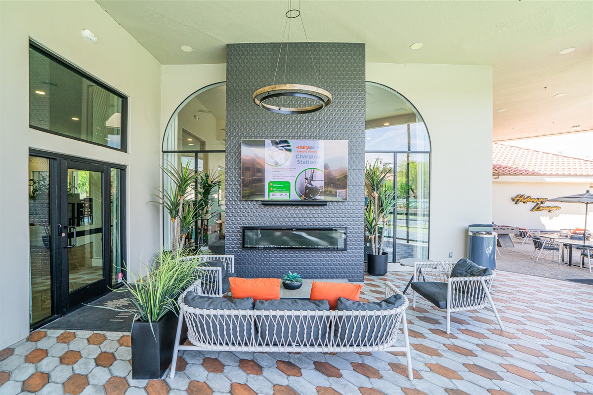 Vibrant courtyard with games, string lights, and lush green space for fun and relaxation.