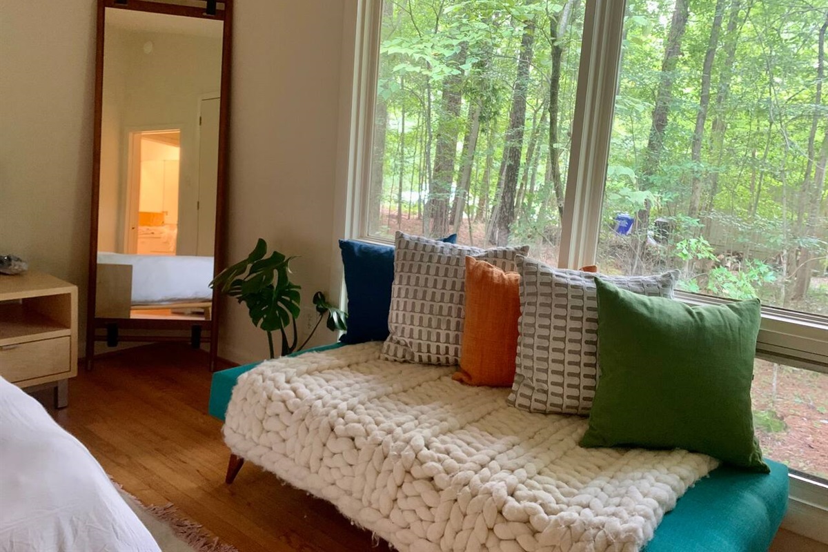 The master bedroom looks into the woods. Close the shades if you like, or take a seat at this custom built bench.