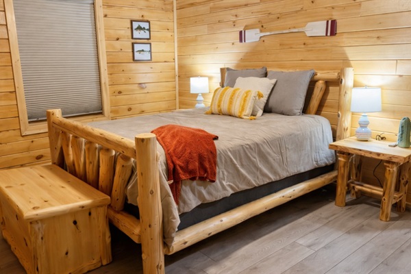 Cozy main-floor guest bedroom featuring a queen bed, rustic log furnishings, and bathroom just across the hall