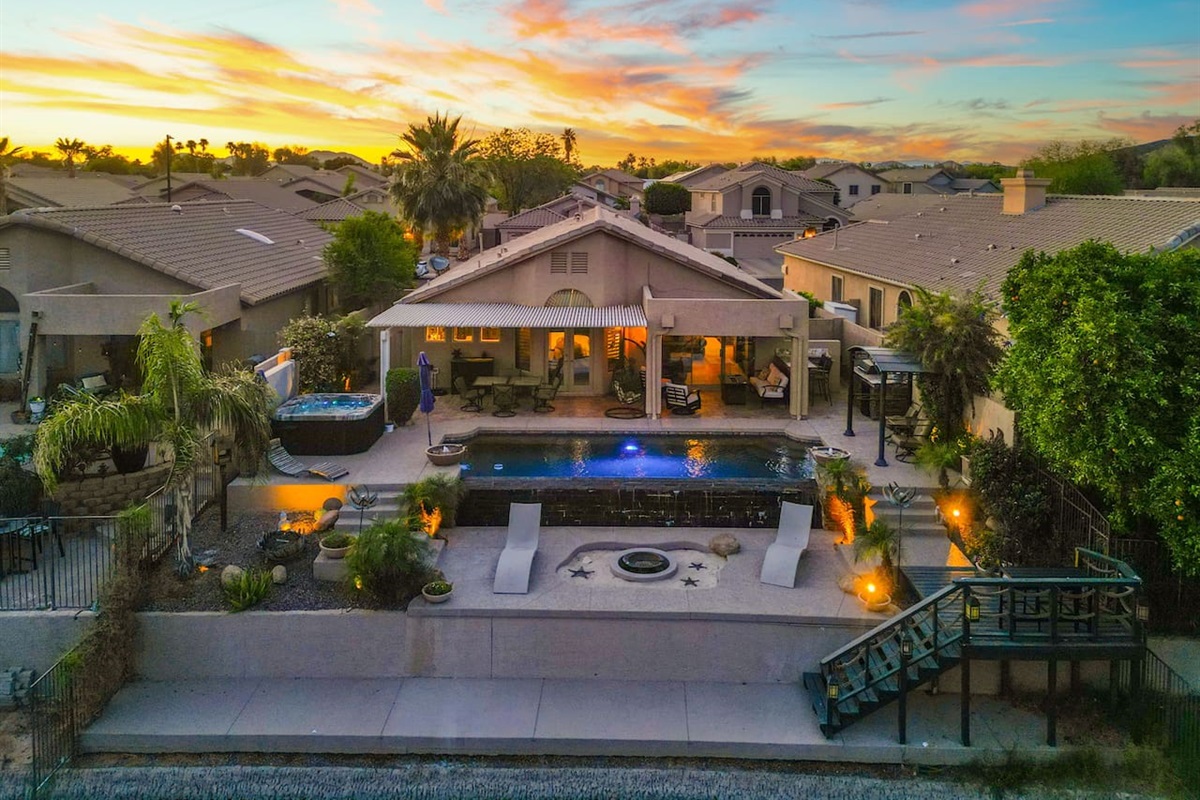 Your private backyard paradise, captured at golden hour — a sparkling pool with spa, covered patio, and fire pit create the perfect setting for evening cocktails and starlit conversations.