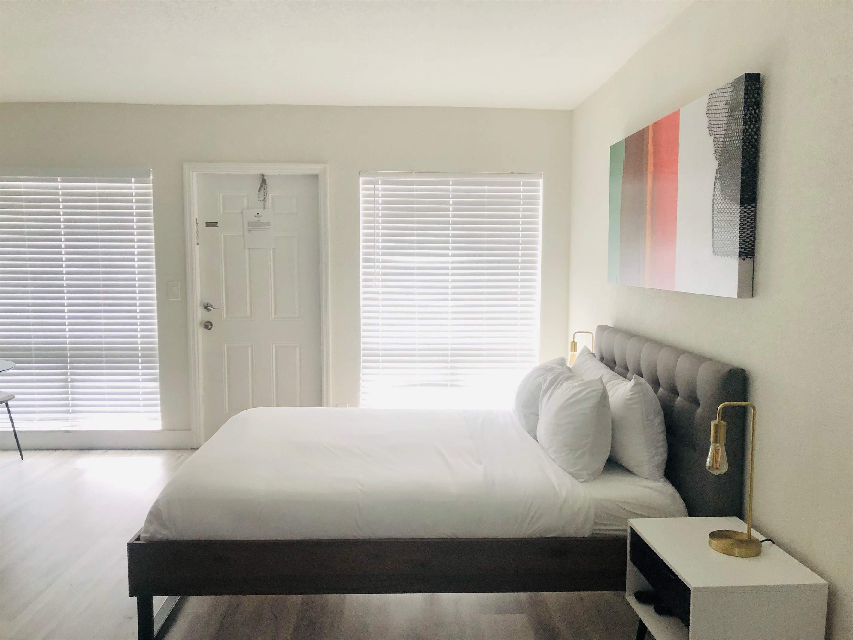 View of queen bed towards apartment entry with floor to ceiling windows.