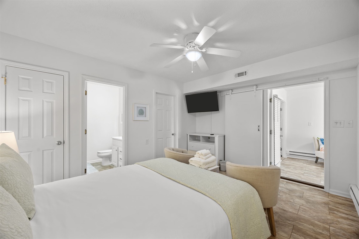 Comfortable ground-level bedroom with queen bed, TV, and seating area, plus easy access to the private bathroom