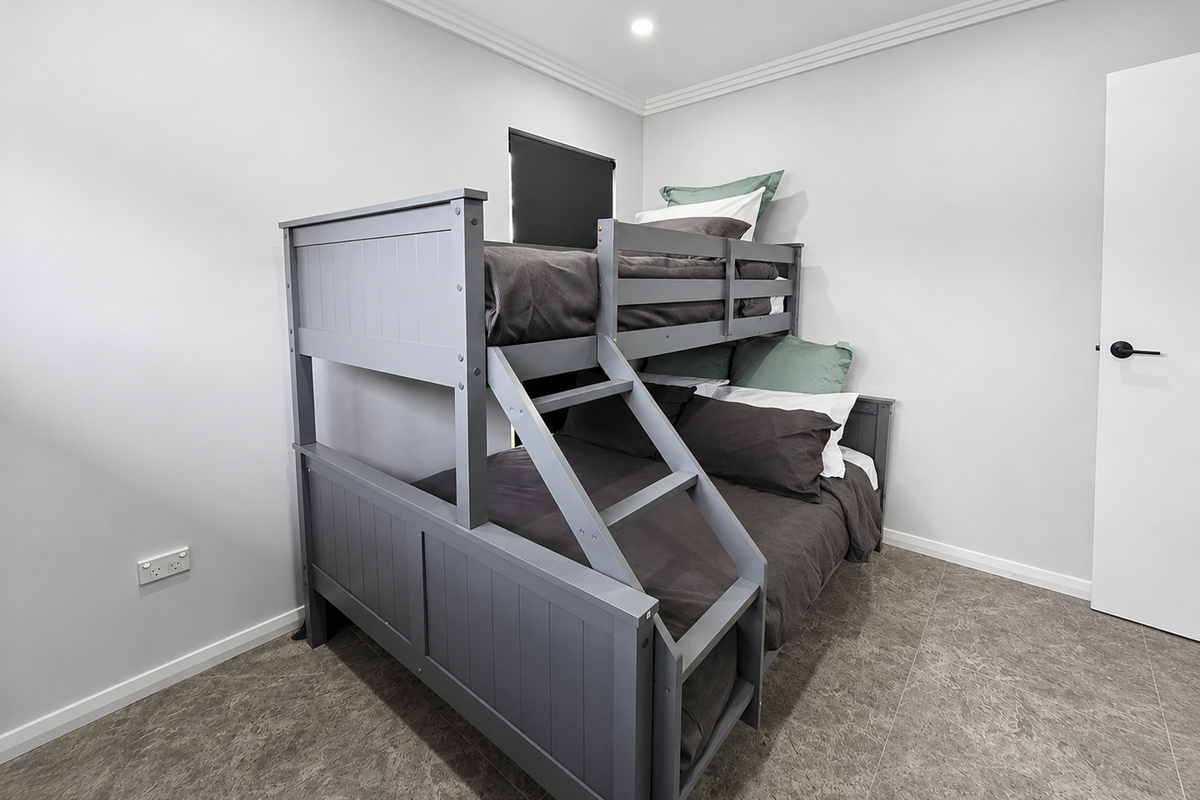 This bedroom includes a tri-bunk with a double lower bed, single upper bed and built-in ladder.