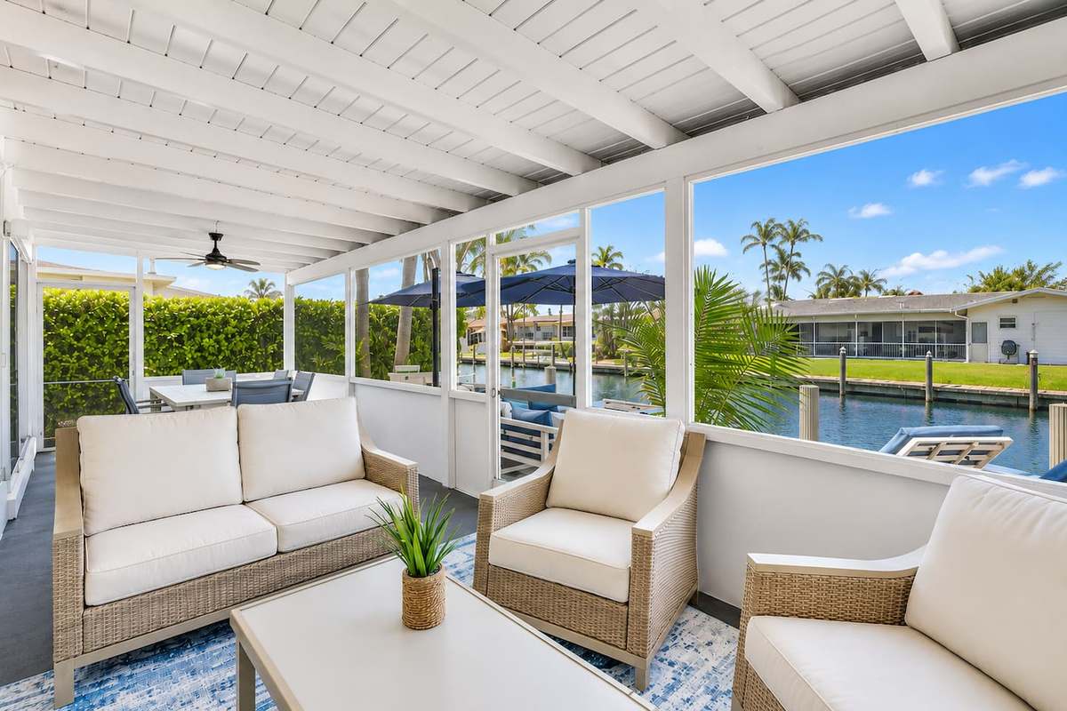 Covered waterfront patio with comfortable lounge seating and peaceful canal views, perfect for morning coffee or relaxing by the water.