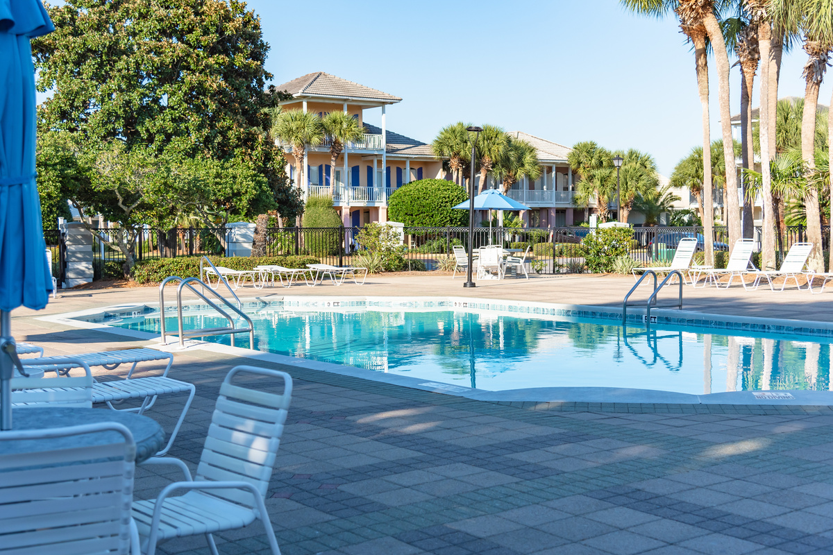 Community pool with lounge chairs and palm‑lined deck