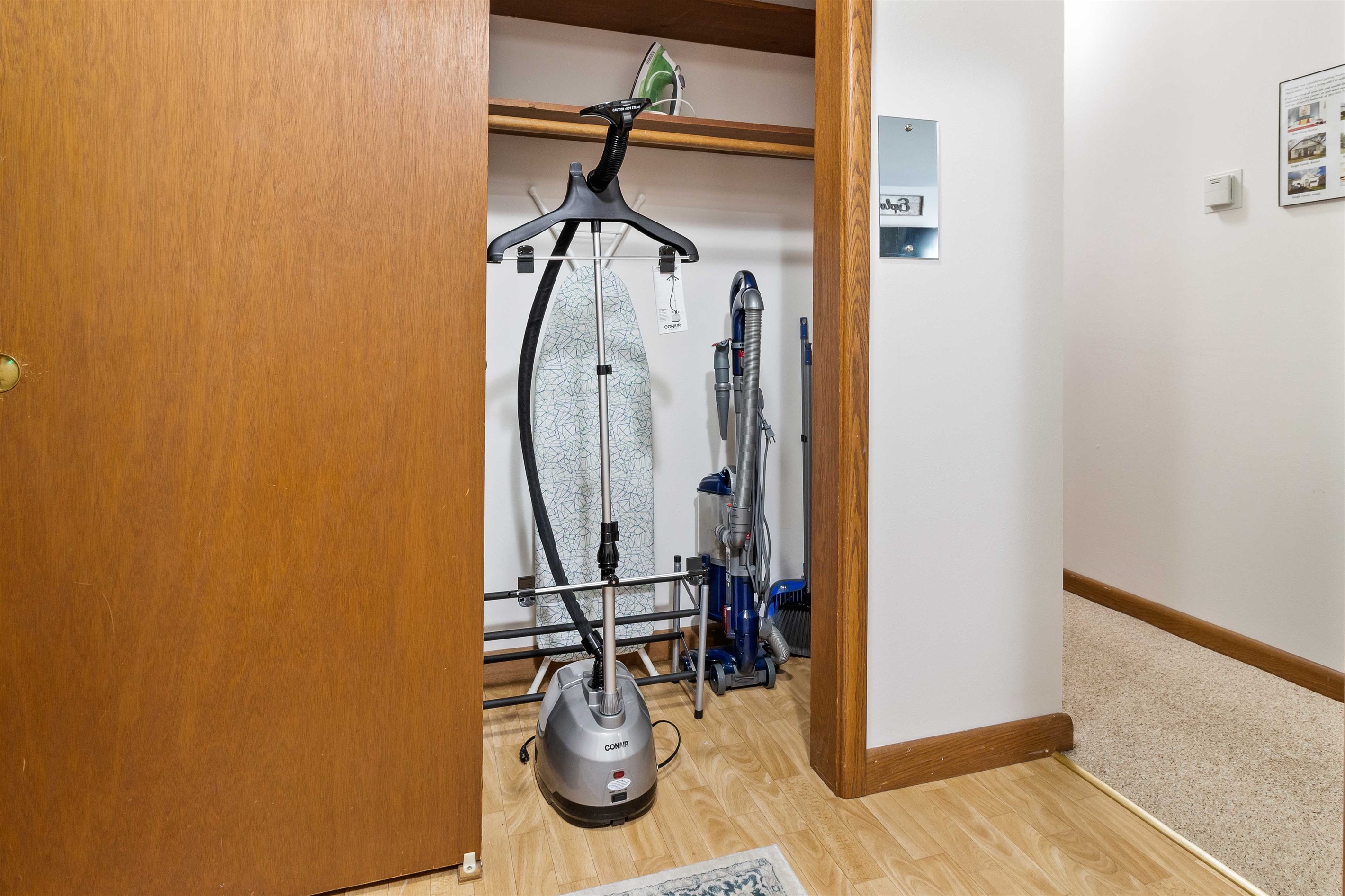 Entryway closet with ironing board, vacuum, and professional steamer to make sure your suits are pressed.