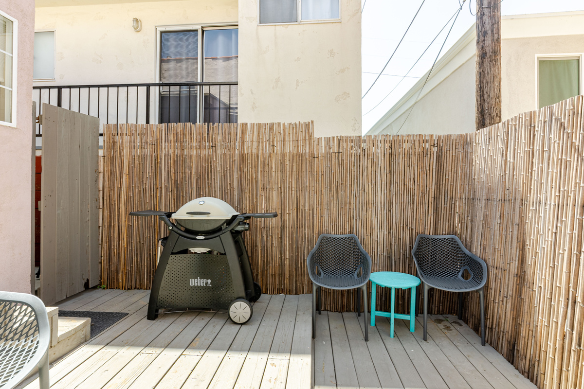 A cozy shared deck in the back of the house includes a Weber BBQ grill and outdoor furniture