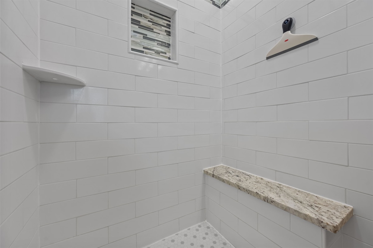 Walk-in tile shower with built-in shelf and glass door