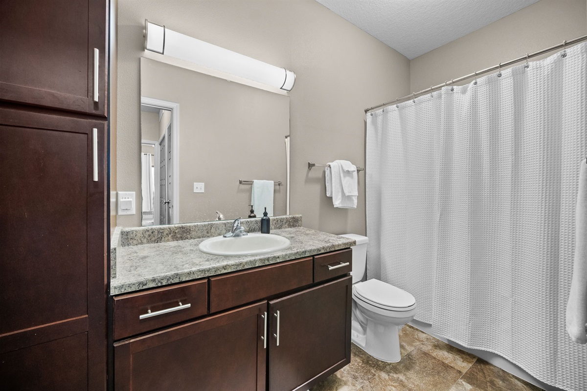 The bathroom has plenty of storage options as well as an adjustable handheld shower head.