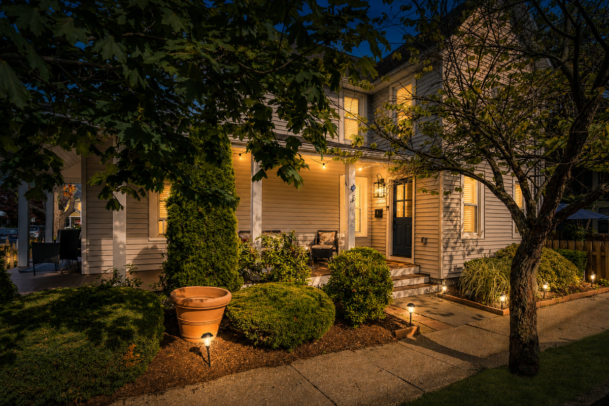 Come home to this every evening. The historic Victorian glows at blue hour, porch lights on, just a short stroll back from the beach and steps from Main Street.