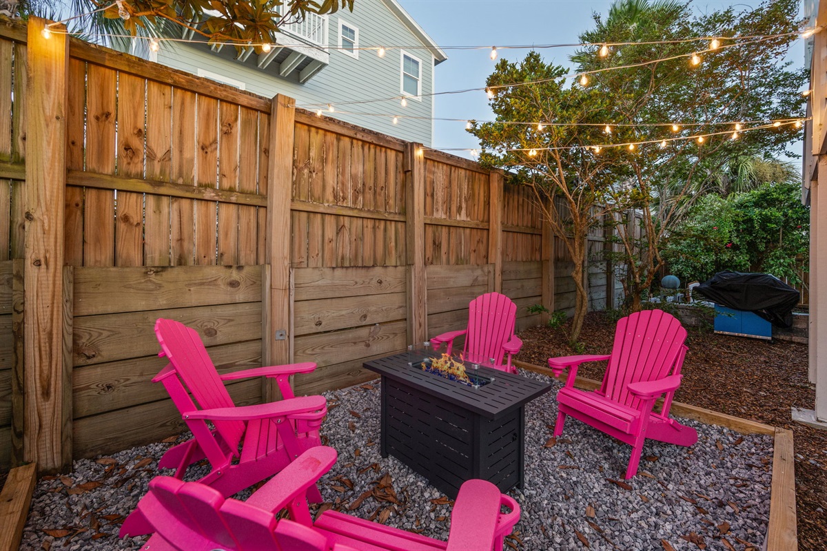 This photo features four sturdy pink outdoor chairs with built-in cup holders, arranged around a propane fire feature. We provide the propane, so you can just sit back, relax, and enjoy a cozy fire under the stars!