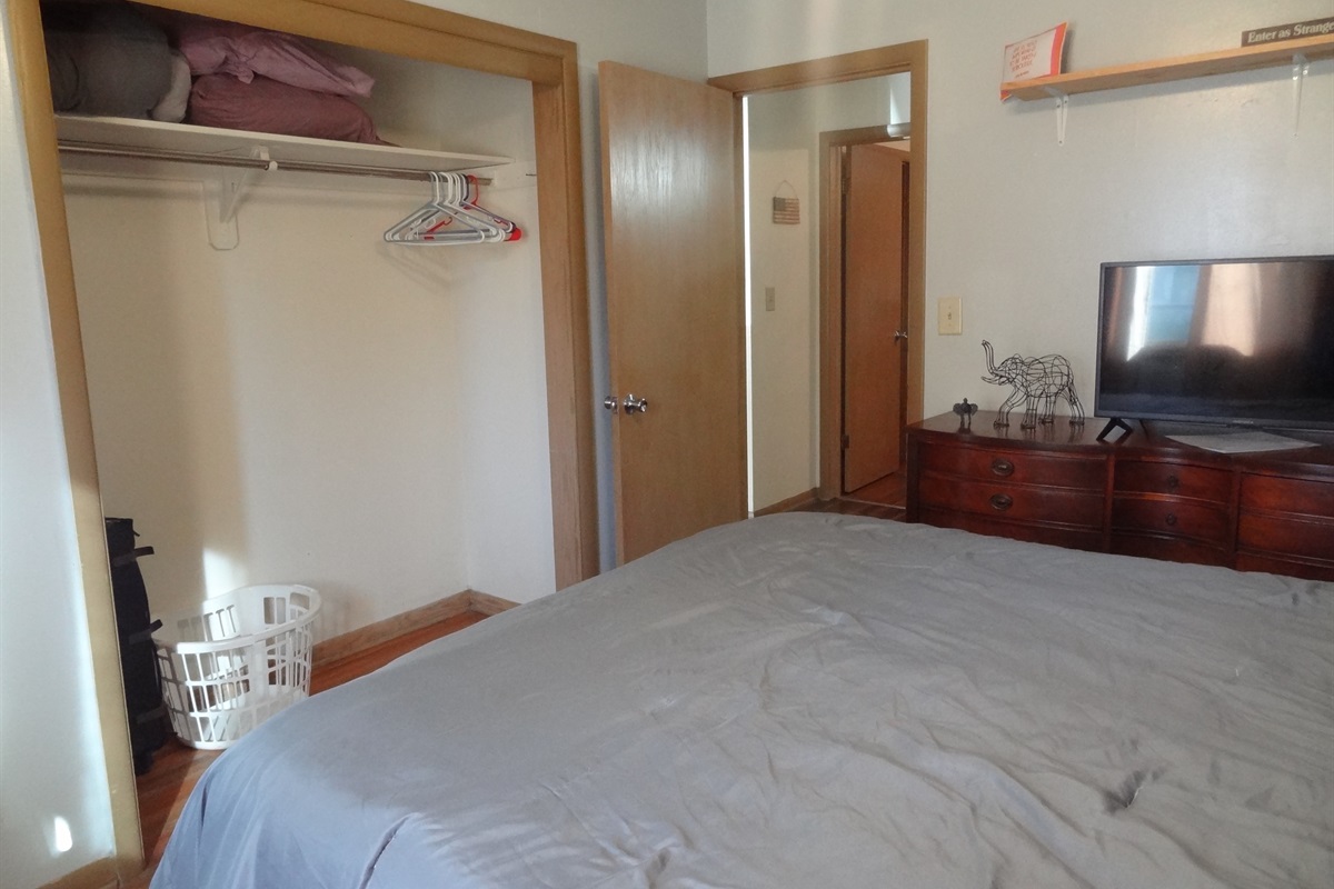 Master bedroom with queen bed, Roku smart TV, dresser, ceiling fan, and desk