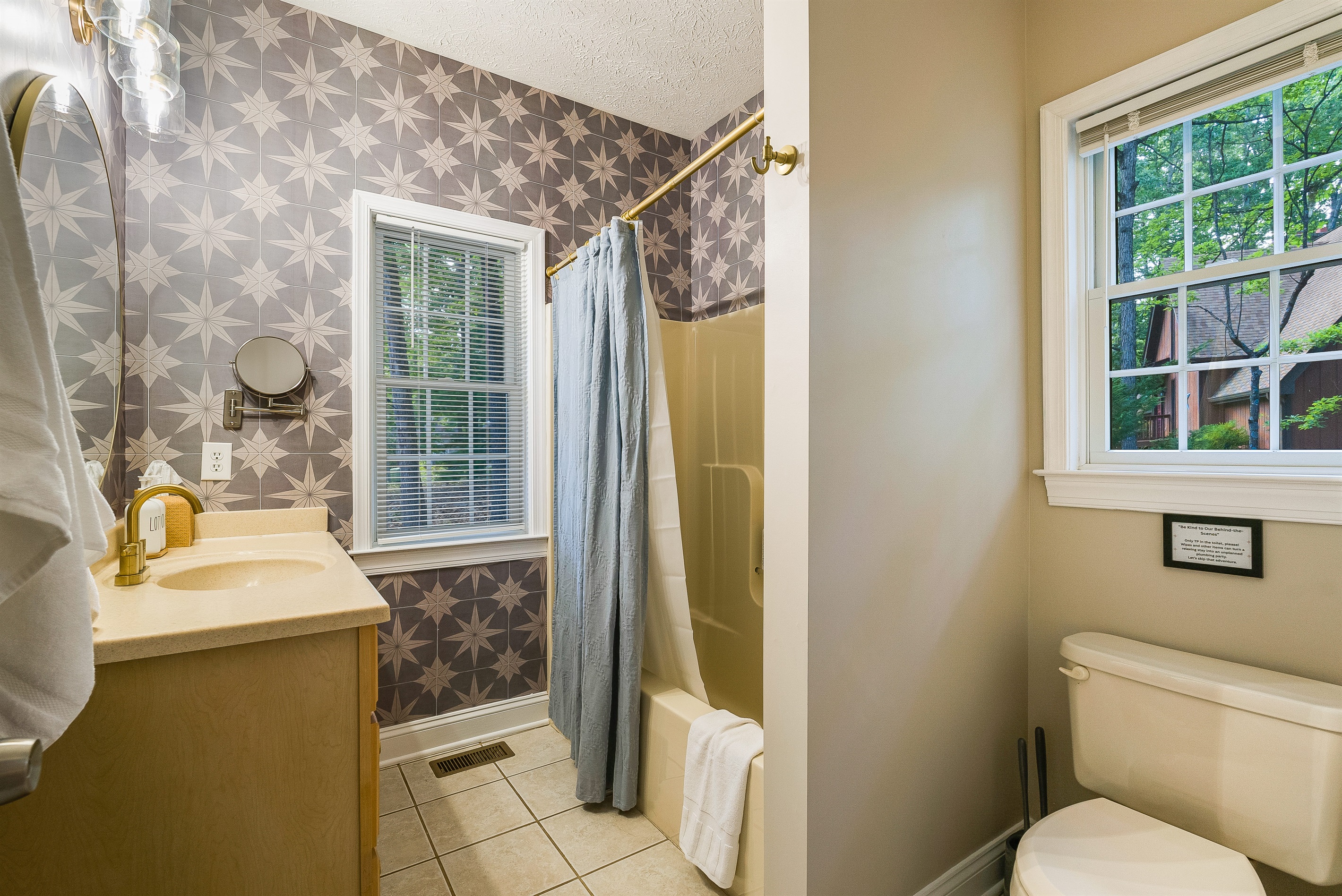 Bright full bath with playful patterned wallpaper — stocked with the essentials so you can pack light