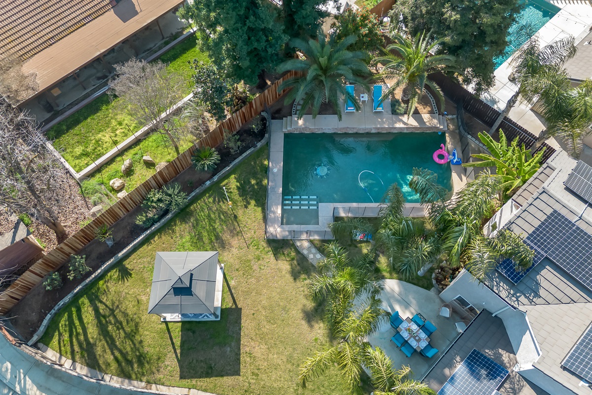 Spacious backyard with a private pool, large grassy play area, and shaded gazebo—plenty of room for kids to play and everyone to relax together.