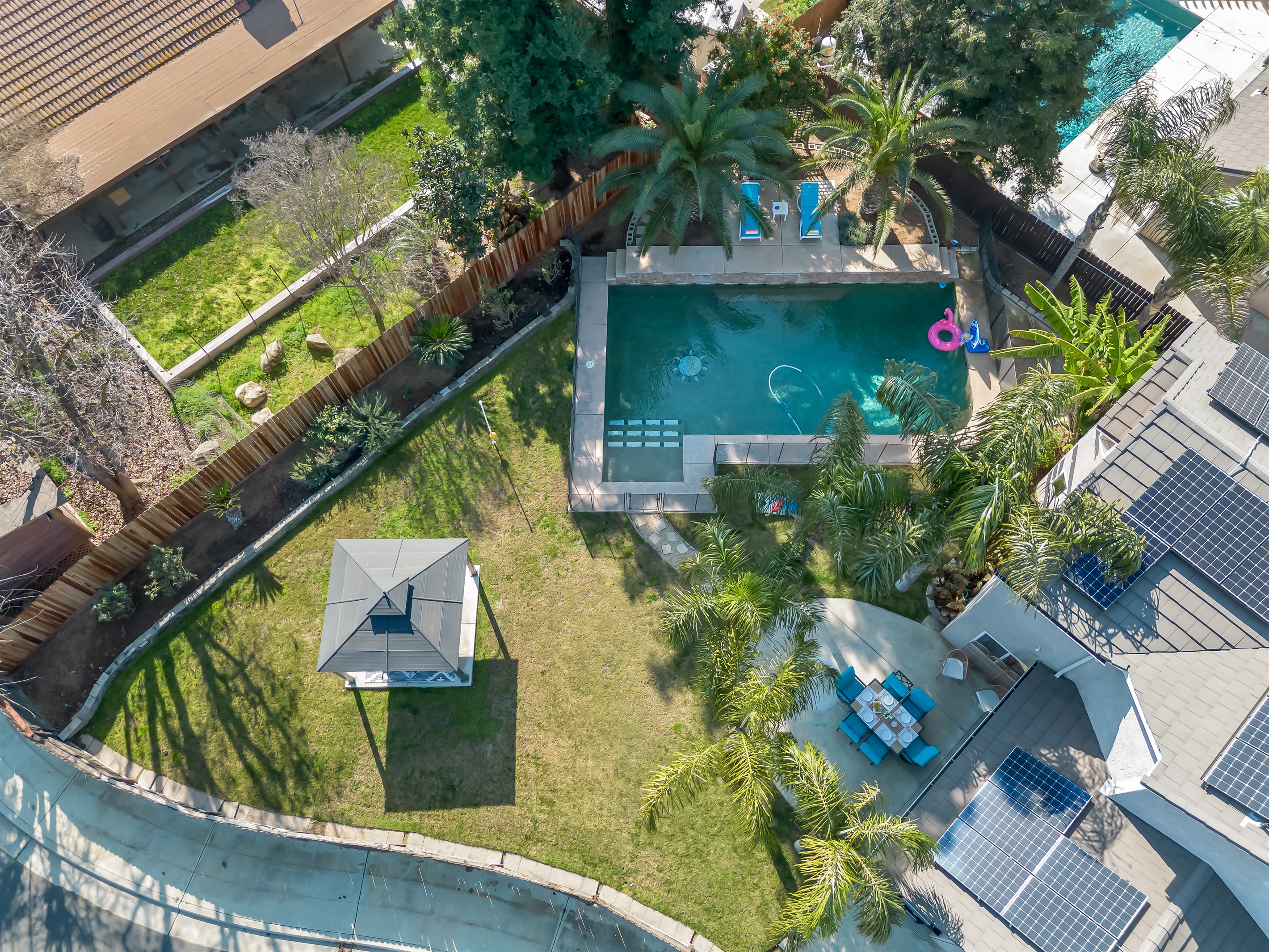 Spacious backyard with a private pool, large grassy play area, and shaded gazebo—plenty of room for kids to play and everyone to relax together.