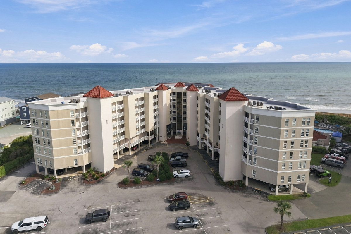 Aerial view of the resort property, surrounding buildings, and open ocean view.