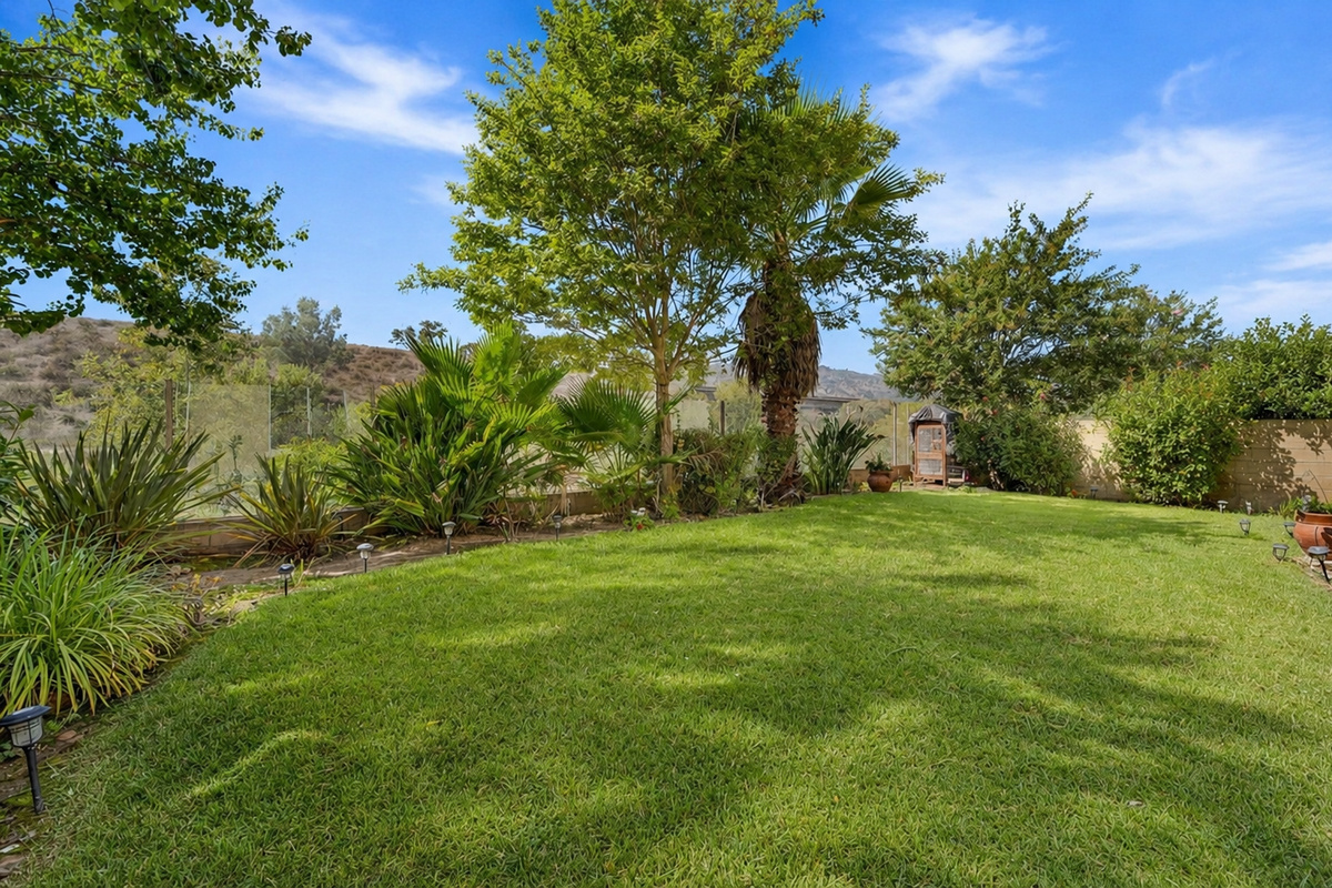 Backyard lawn with green space, mature trees, and a quiet spot to enjoy time outside.