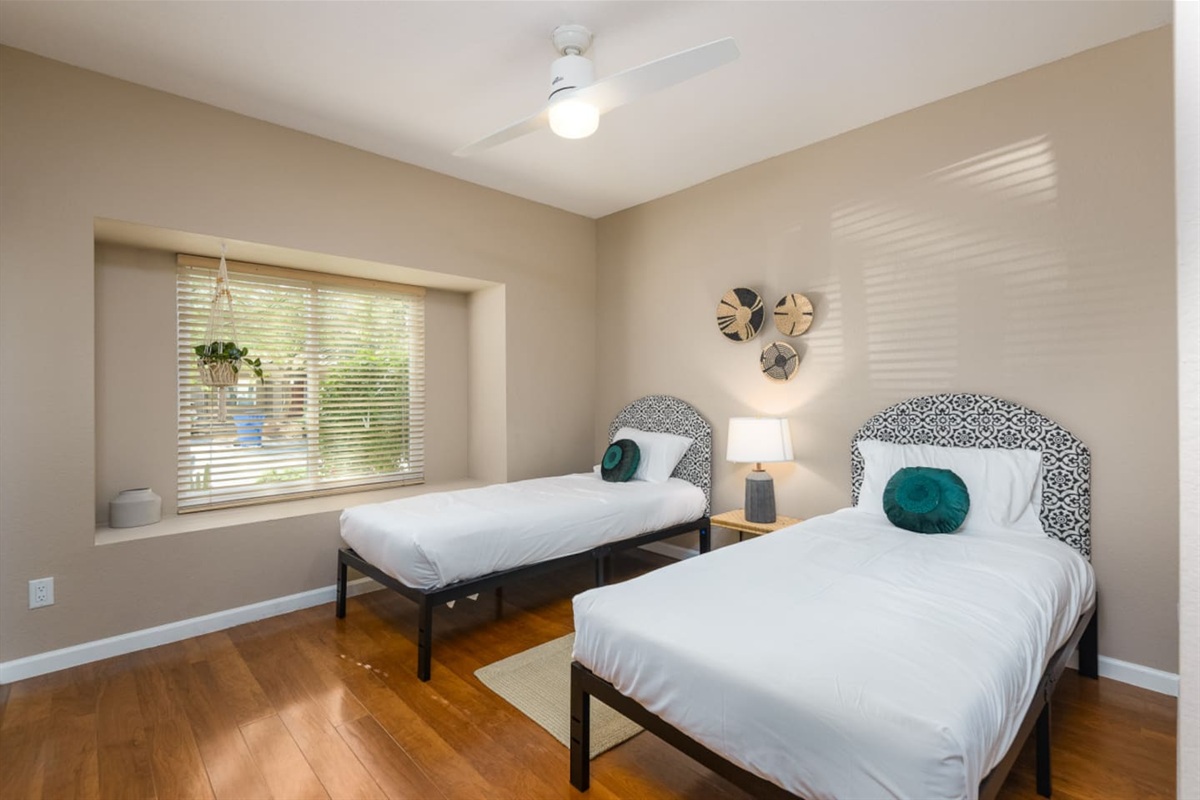 Guest Bedroom 3 with two twin beds, bedside table, ceiling fan, and a simple setup that works well for kids or extra guests.