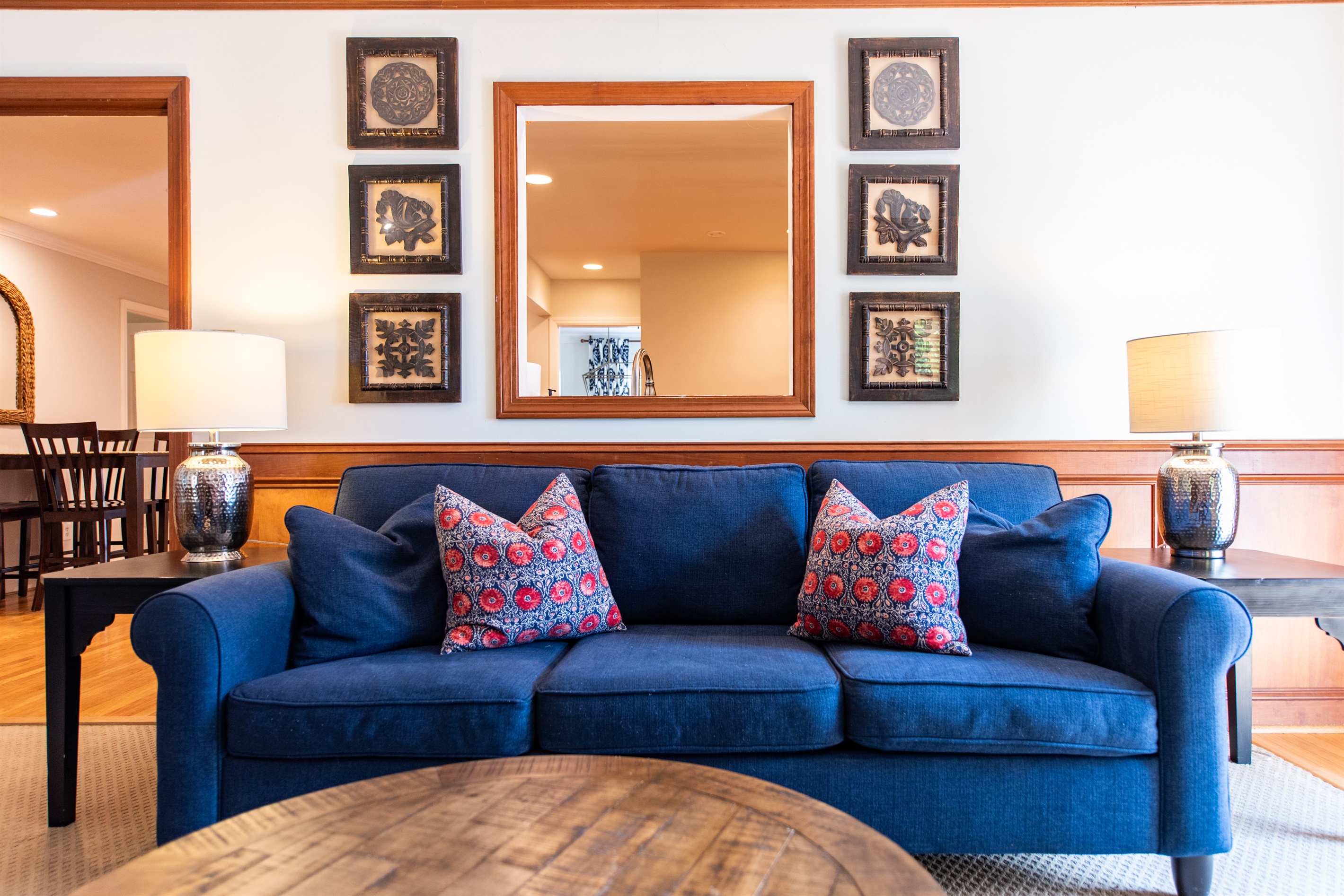 Charming home in Louisville, KY, on the Bourbon Trail. Blue sofa and armchair, red pillows, wooden coffee table, lamps, framed art, and patterned curtains. Cozy and stylish retreat!