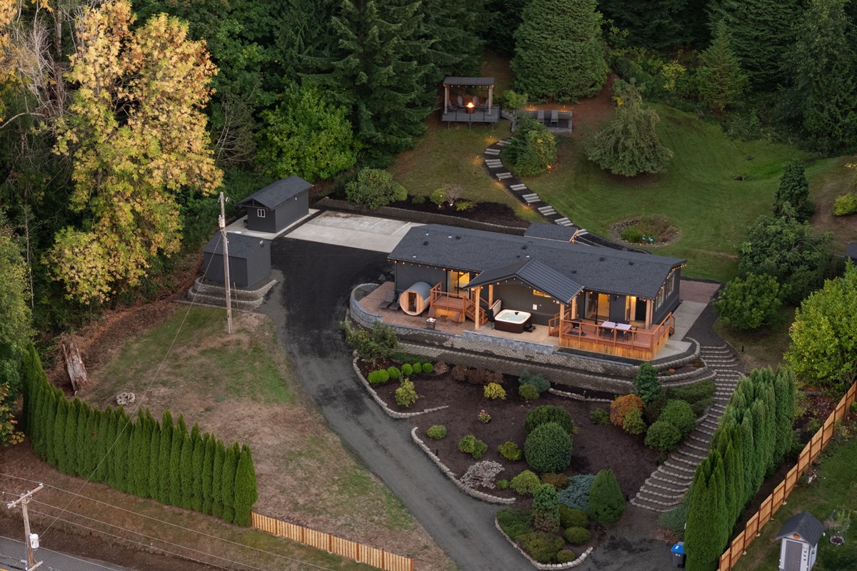 Evening settles over the glowing home, embraced by expansive, tranquil grounds