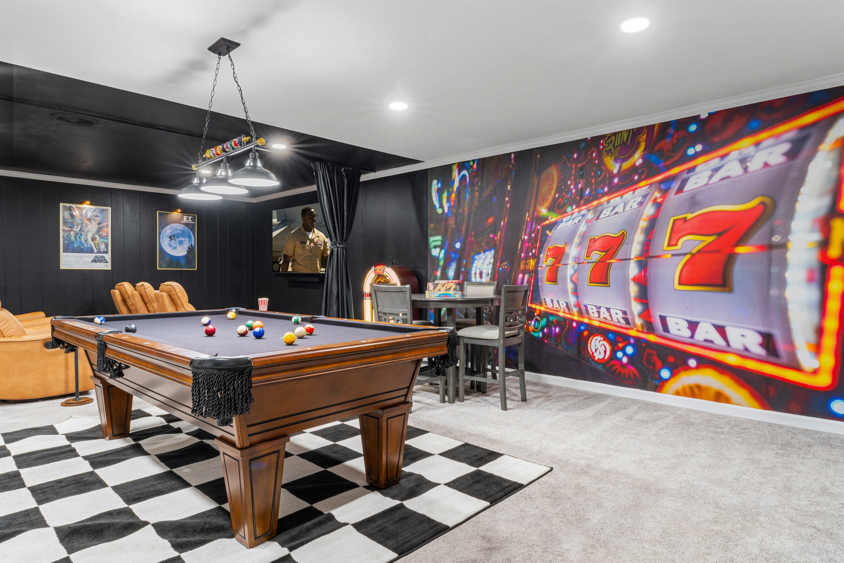 Vibrant game room with a full-size pool table, arcade games, casino-style mural, board game area, seating for plenty, and bar setup with ice maker, microwave, minifridge and TV — the ultimate entertainment space