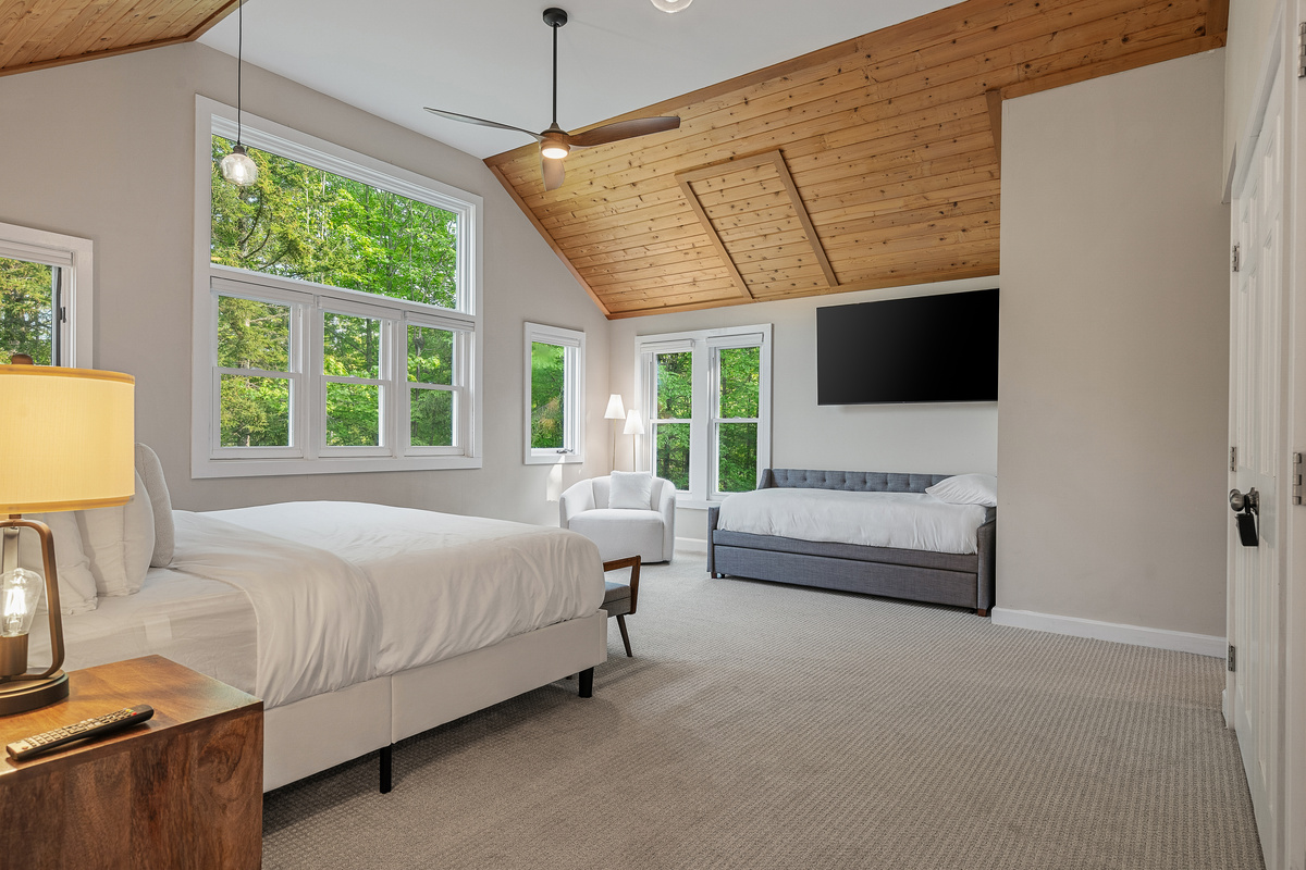 King bedroom with pitched pine ceiling, TV and sofa at this Stratton area rental