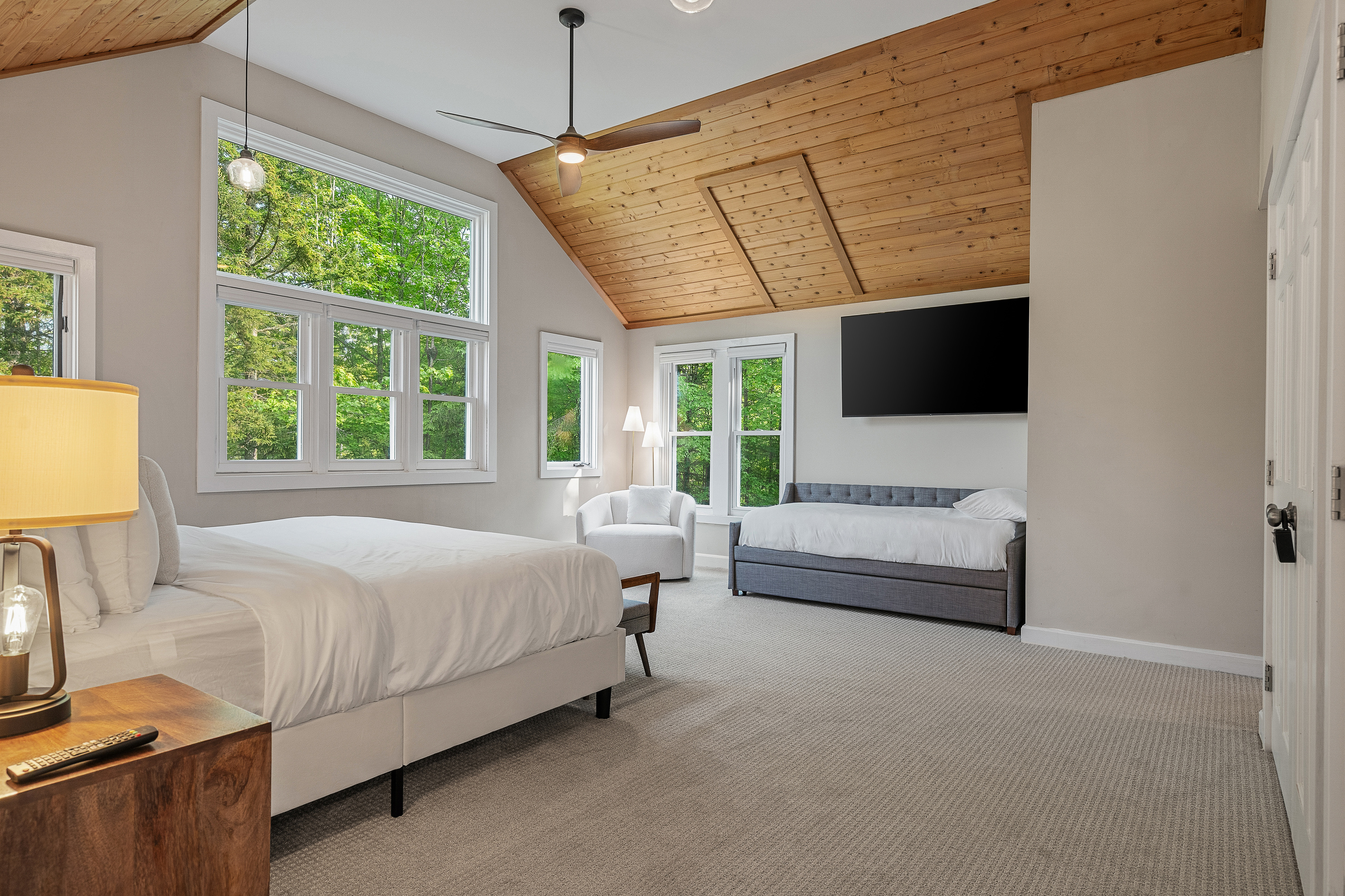 King bedroom with pitched pine ceiling, TV and sofa at this Stratton area rental
