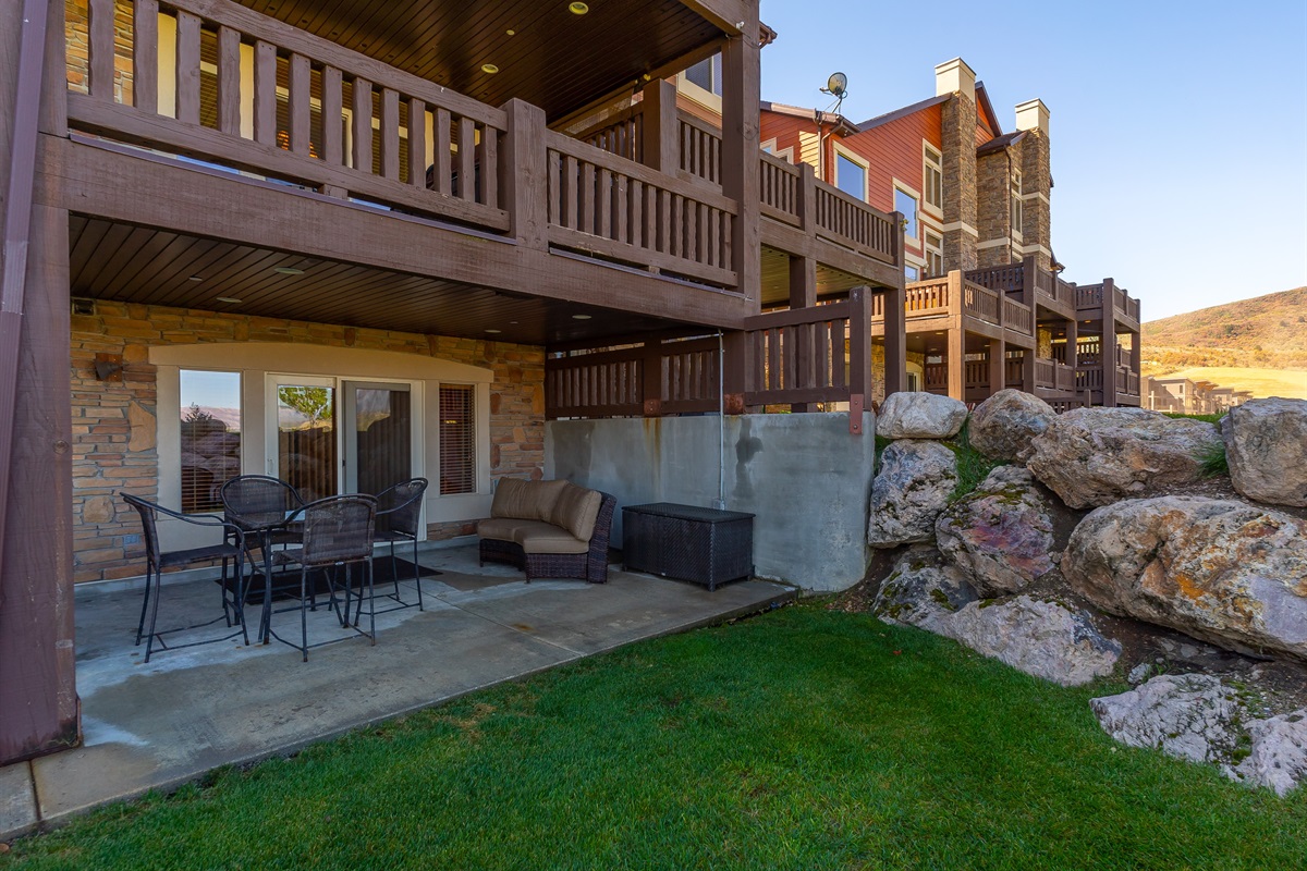Private lower-level patio with outdoor seating and direct access to open green space.