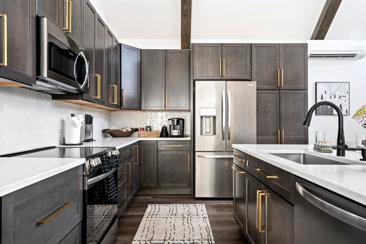 Sleek and stylish kitchen goals! Love the modern cabinets, gold hardware, and contrasting countertops.