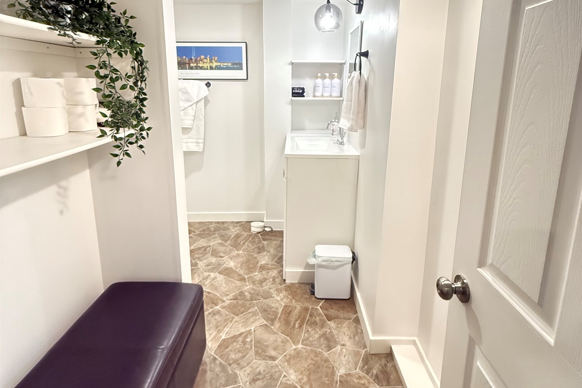 Bathroom with walk-in shower, towels, and open shelving for personal items.