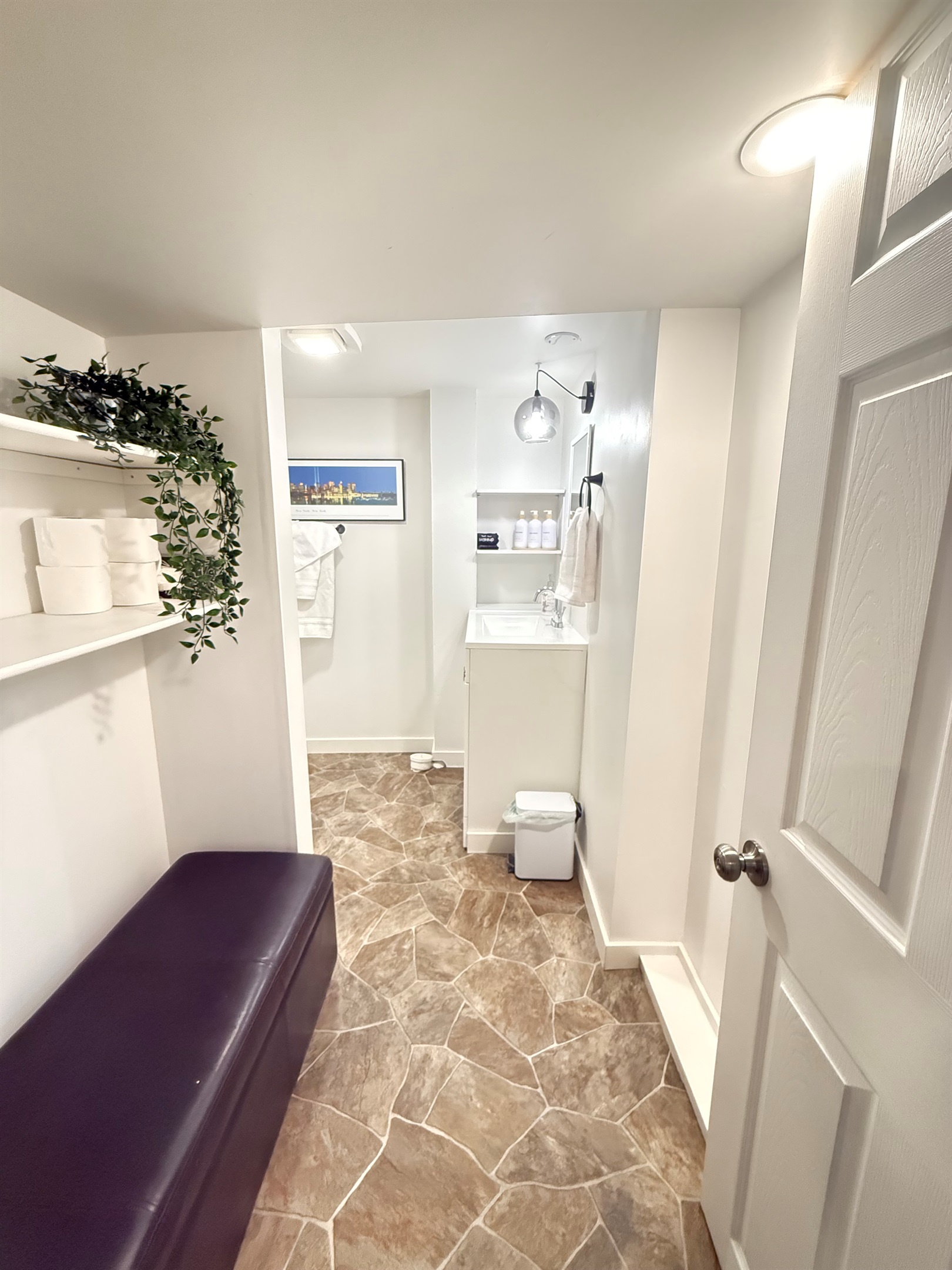 Bathroom with walk-in shower, towels, and open shelving for personal items.
