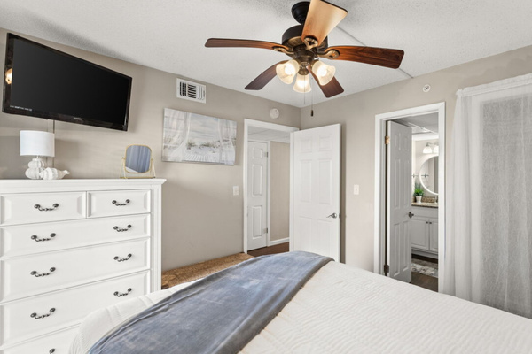 Guest bedroom with a queen bed, clothing storage, ceiling fan, and smart TV