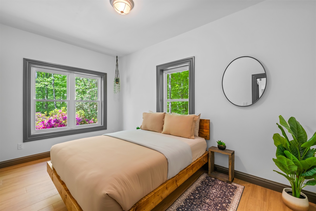 Guest bedroom with a queen bed, closet, and front home facing with natural views.
