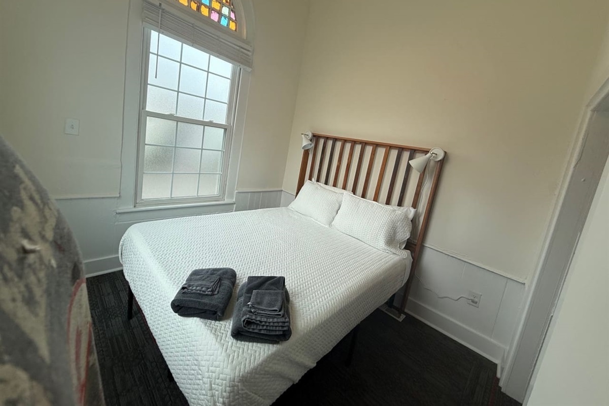 Inviting front bedroom with a comfortable queen-size bed, crisp linens, soft lighting, and all the must-have amenities for a relaxing retreat.