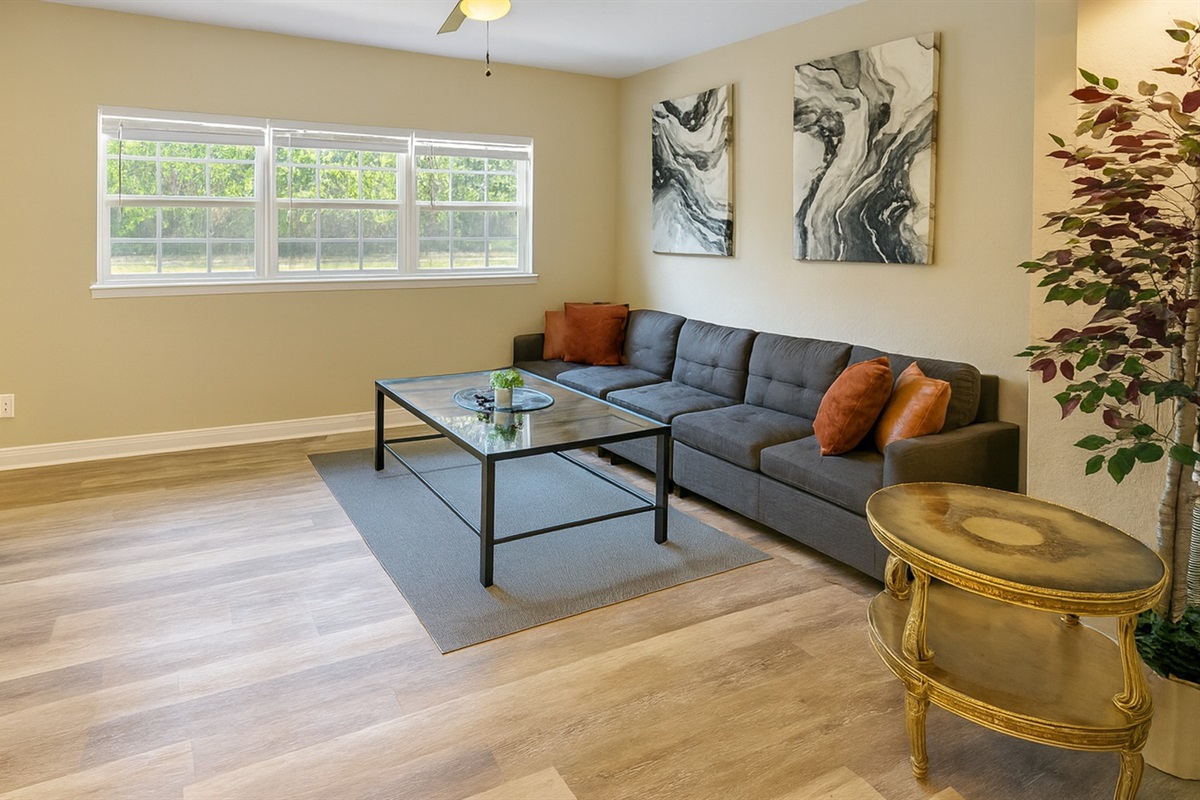 Secondary living space with sectional sofa, stylish artwork and large windows—great for game nights or reading after exploring Madeira Beach and Johns Pass from our Seminole midterm rental.