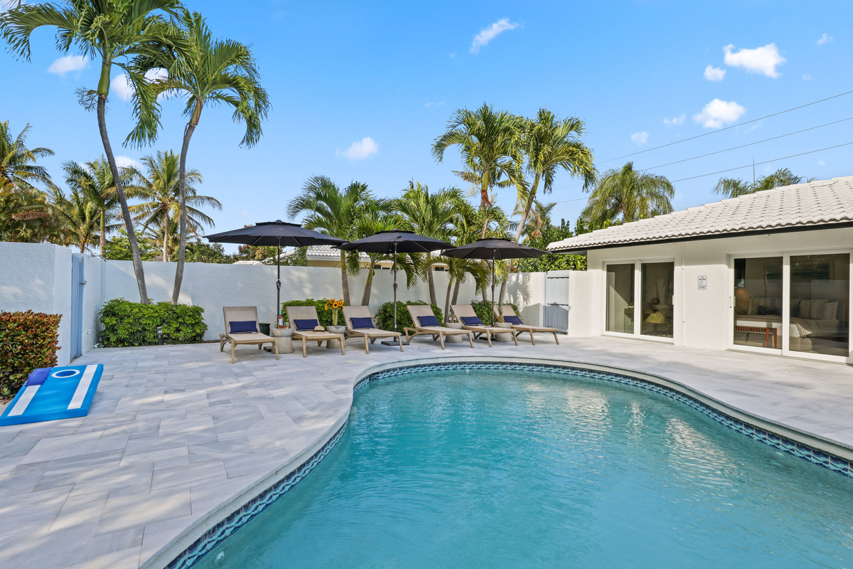 Stretch out by the private pool with shaded loungers, umbrellas, palm trees, and cornhole nearby for easy vacation afternoons.