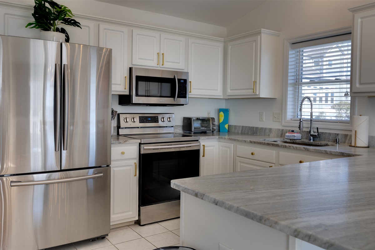 Fully equipped, modern kitchen with stainless steel appliances, generous counter space, and a large island