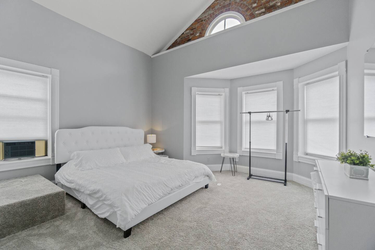 Spacious and neat king-sized bedroom with a clean white interior, offering a serene and luxurious retreat.