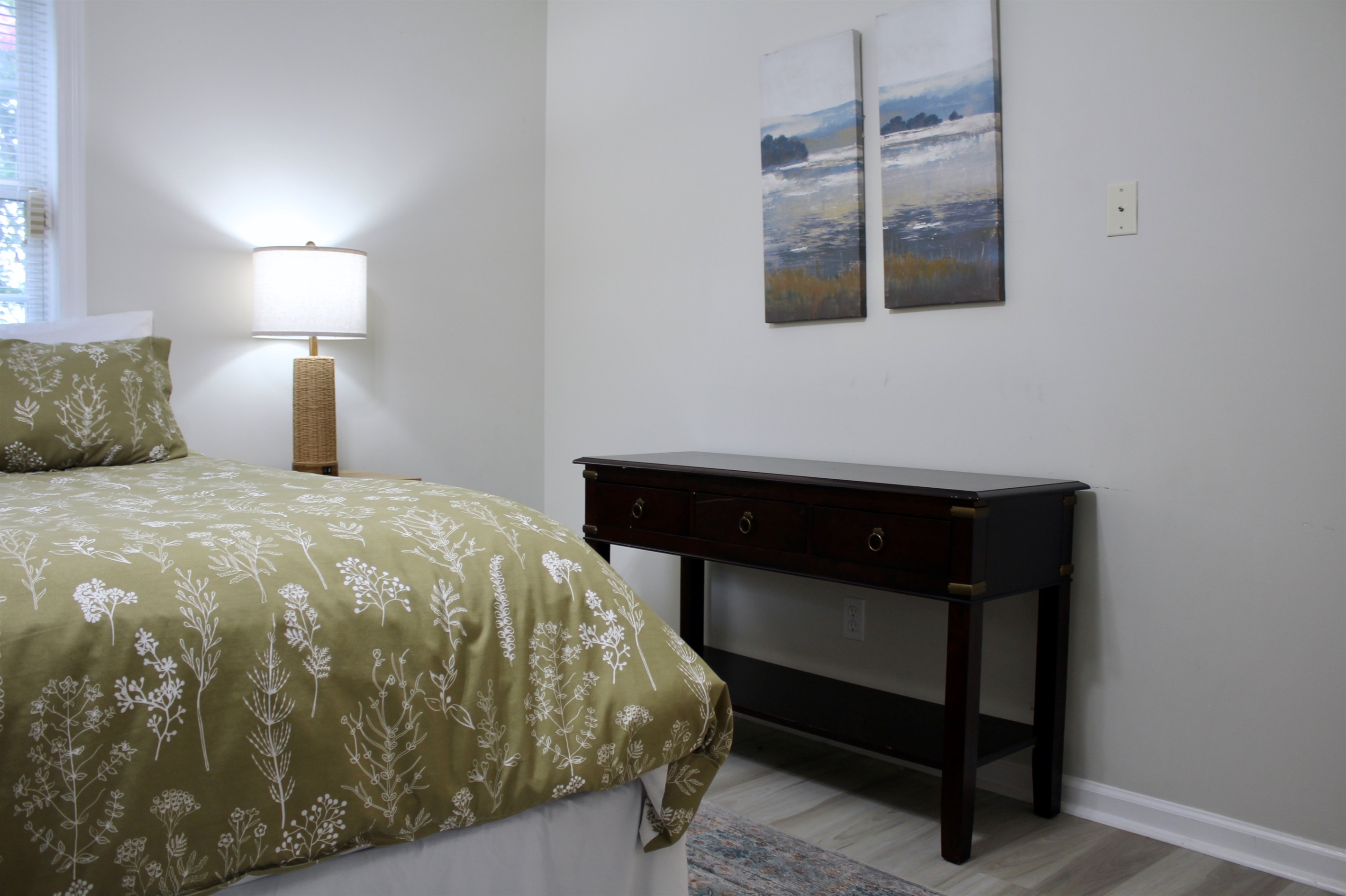 Scenic artwork and soft linens complete this calming bedroom escape.