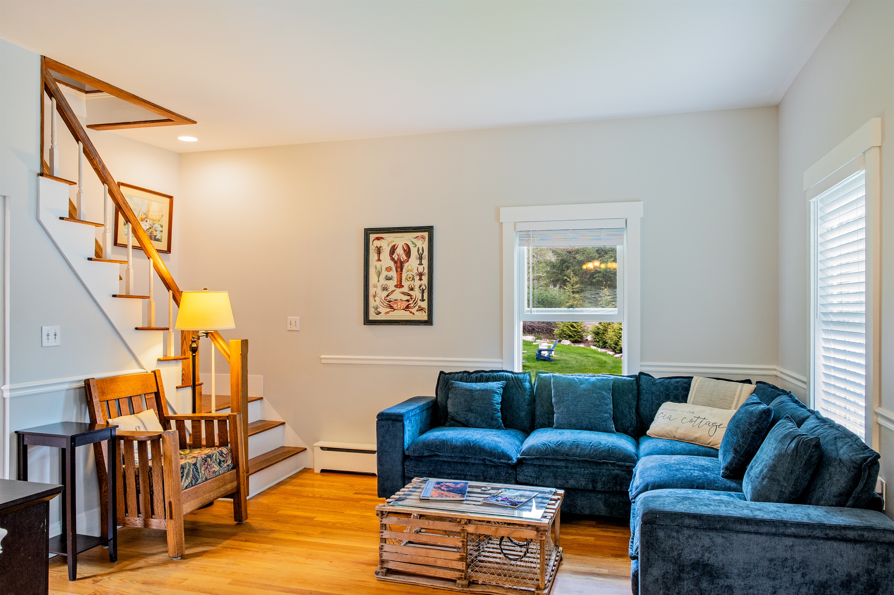 Classic Maine soul in Hall Quarry. This view features our new navy sectional and a curated antique armchair alongside historic MDI maps. Relax in this 1880 Quiet Side basecamp, perfectly positioned for exploring Acadia and Southwest Harbor.