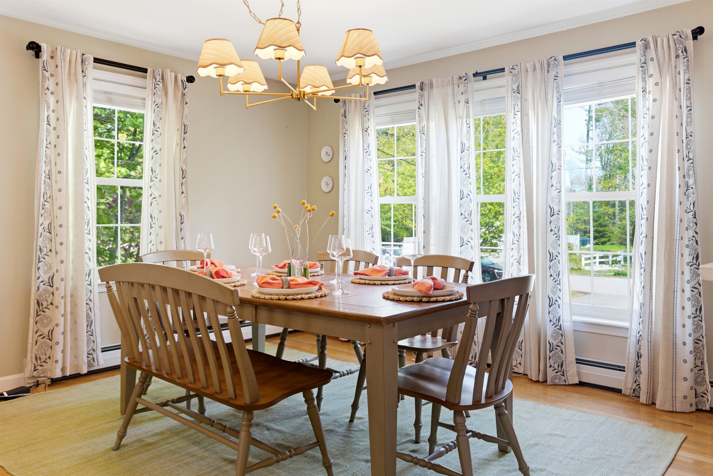 A sunlit dining space where large windows enhance the open feel of the room, complemented by carefully arranged cutlery for shared meals and gatherings.