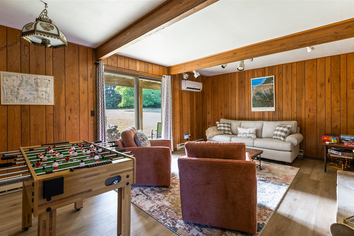 A cozy game room with warm wood-paneled walls, plush seating, and a foosball table—perfect for family fun or relaxing evenings together.