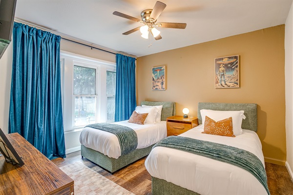 Fun twin bedroom with playful alien decor, bright windows, and luxury bedding