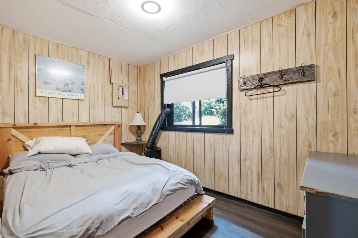 Cozy bedroom with wood-paneled walls and natural light