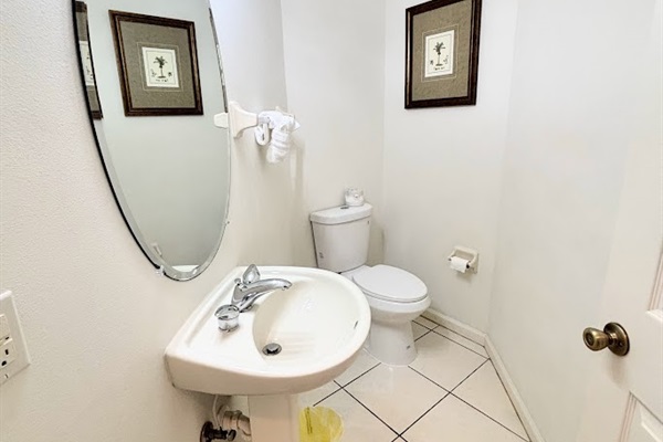 Convenient half bathroom with pedestal sink, tile flooring, and clean neutral finishes.