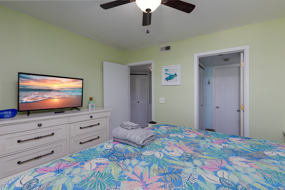Bright bedroom featuring smart TV, spacious dresser, and beach-inspired accents