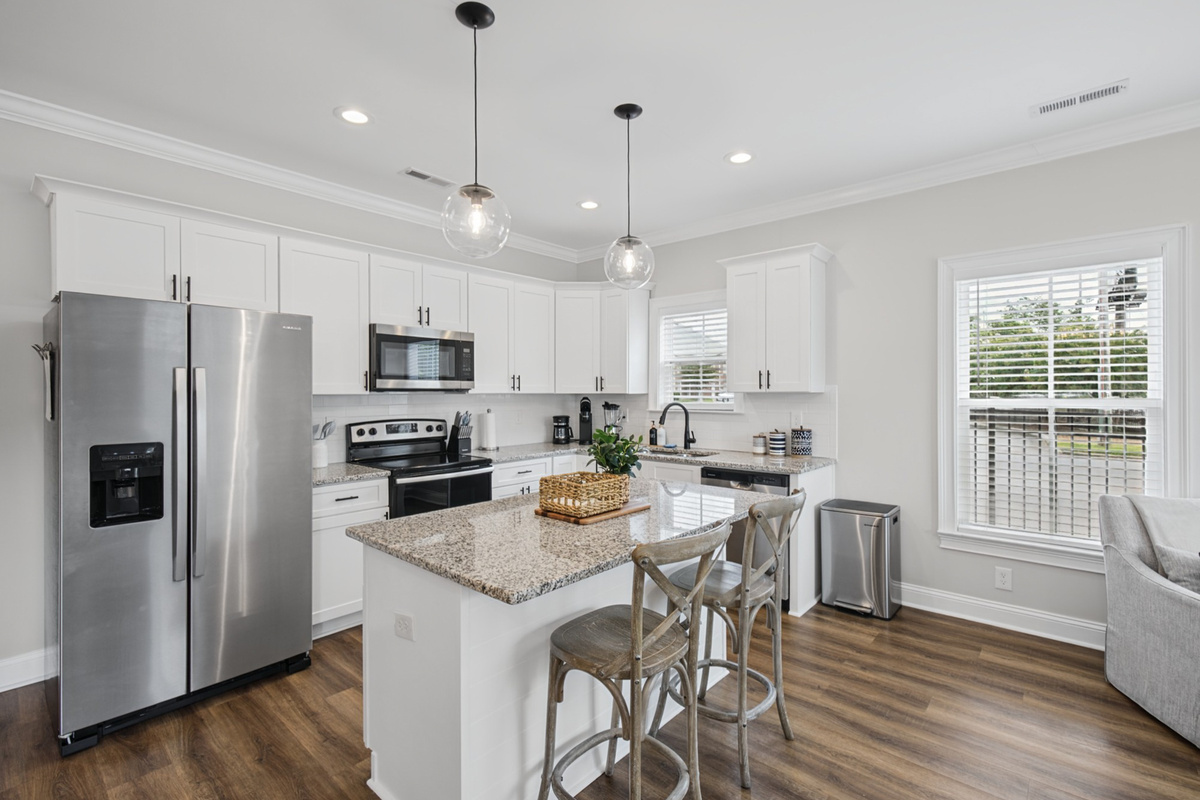 Bright white kitchen with granite counters and full-size stainless appliances
