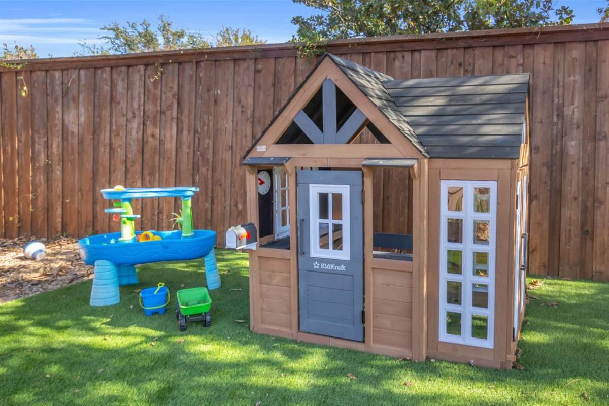 Beautifully staged children’s play space with a KidKraft cottage, water table, and outdoor toys, offering hours of fun in a safe, private backyard.